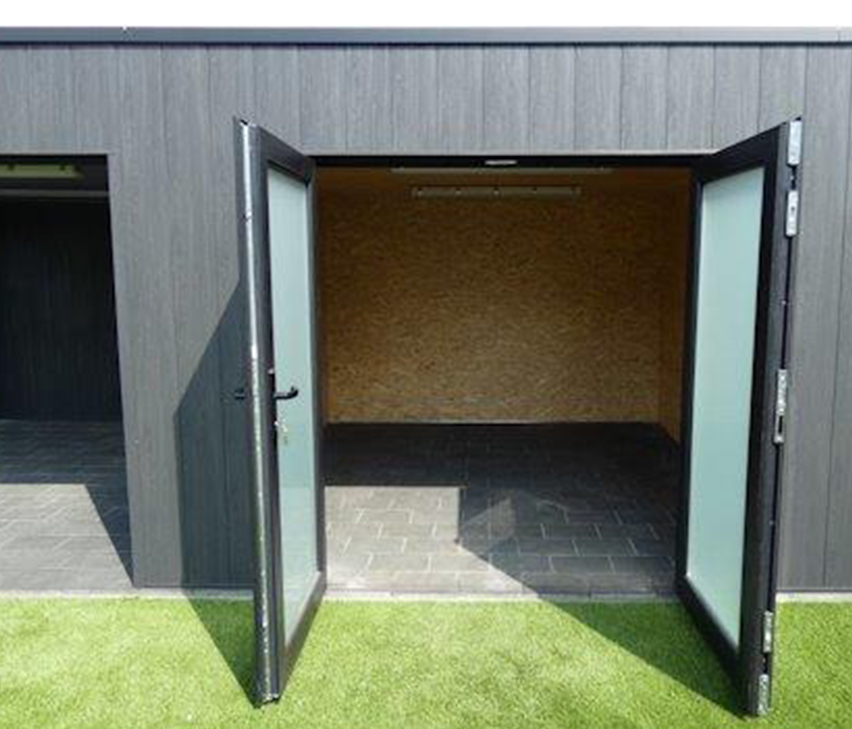 Bijgebouw met donkere houten beplanking en dubbele deuren met matglas, open naar het gazon.