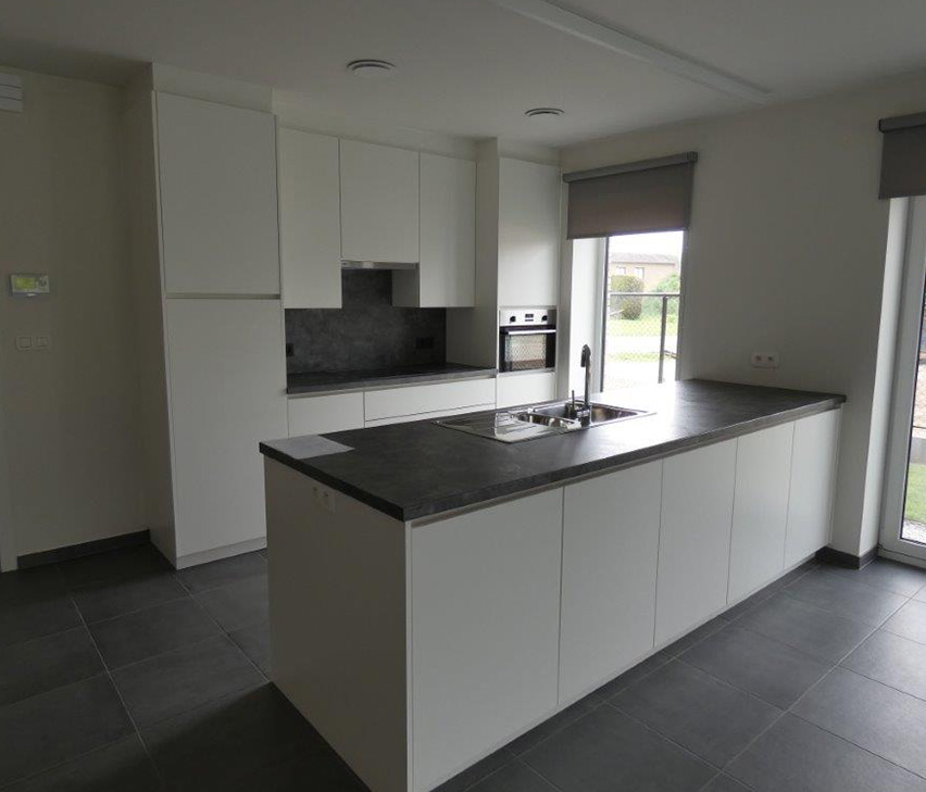 Afgewerkte leefkeuken met een wit keukeneiland en een donker werkblad, in een nieuwbouwwoning.