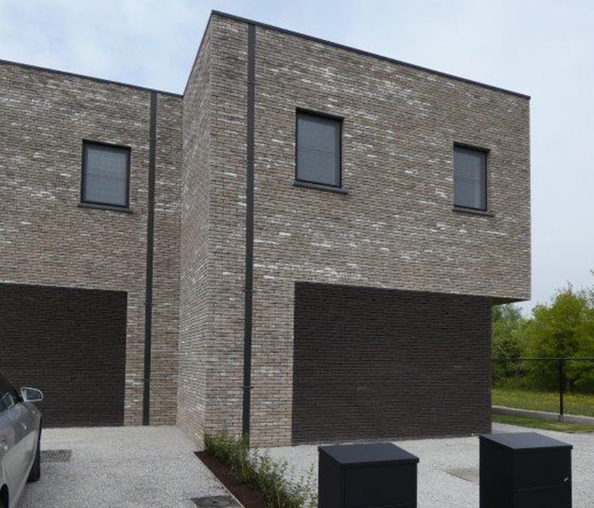 Dezelfde twee woningen vanuit een andere hoek, met de zijgevel en de garagepoorten in het beeld.